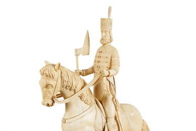 Auf einem Pferd steht ein vollbärtiger, schlanker, älterer Herr in Paradeuniform mit ausgestreckten Beinen in den Steigbügeln des Sattels. Mit der Linken hält er die Zügel, in der Rechten eine Barte.