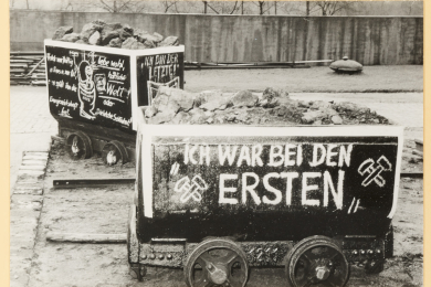 Zwei mit Protest-Zeichnungen versehene Förderwagen in einem Betriebshof. 