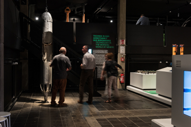 Museumsraum mit Besuchenden und Exponaten, darunter eine Rettungskapsel