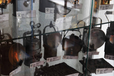 Das Foto zeigt eine Sammlung von historischem Grubengleucht in einer Vitrine.