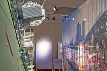 Modell eines Steinkohlenkraftwerkes und dem gegenüber eine Fotografie von einer Demonstration vor dem selben Kraftwerk in einer Ausstellung im Deutschen Bergbau-Museum Bochum 