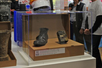 Fritz Wienpahls Schuh in einer Vitrine ausgestellt mit einem Methanmessgerät, das durch Brandspuren gezeichnet ist.