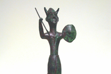 Bronzefigur mit gehörntem Helm, Speer und rundem Schild, auf Ochsenhautbarren stehend