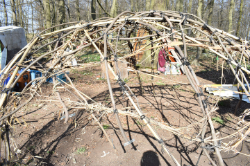 Gebogene Zweige ohne Blätter sind zu einem Halbkreis geformt und mit Seilen verknüpft