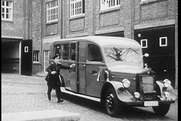 Filmszene, in der ein Grubenwehrmann auf ein abfahrendes Einsatzfahrzeug aufspringt.