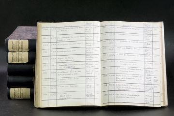 Fünf liegende Eingangsbücher des Deutschen Bergbau-Museums Bochum und ein aufgeschlagenes