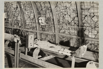 Test der Sensortechnik unter Tage. Ein Bergmann liegt rücklings auf dem Gurtbandförderer. Zu sehen ist der am Schuh angebrachte Sensor.