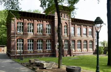 Ein zweigeschossiges Gebäude aus Backstein mit hohen Fenstern