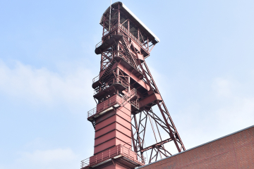 Ein rotes Fördergerüst aus Stahl über einem Maschinenhaus