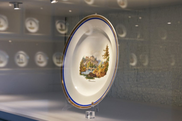 Ein Porzellantelle mit einem Bildmotiv in einer Vitrine